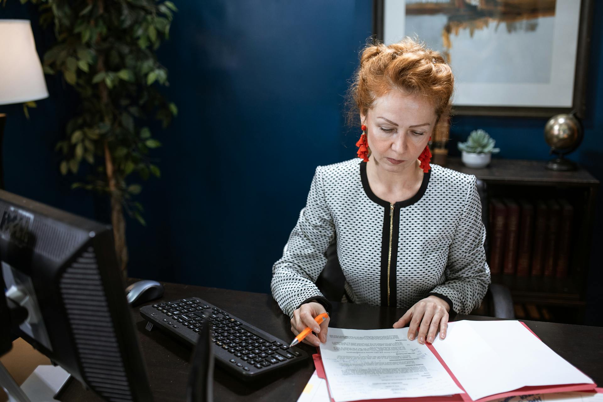 A woman lawyer reviewing documents in a red folder; preparation involved in pre-litigation discovery